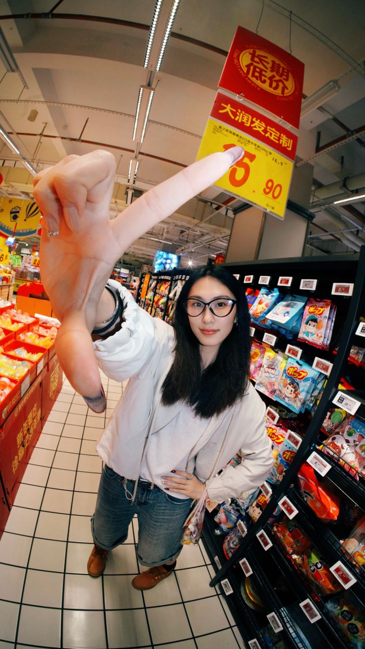 Woman pointing at a sale sign in an Asian supermarket aisle.