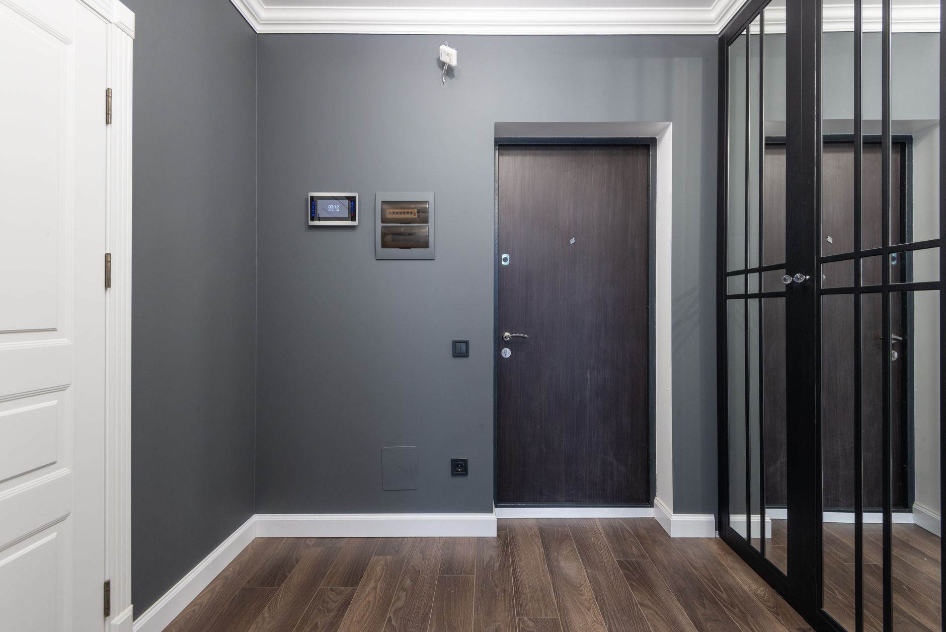 Spacious hall of modern apartment with wardrobe with mirrored doors reflecting wooden parquet floor and gray walls